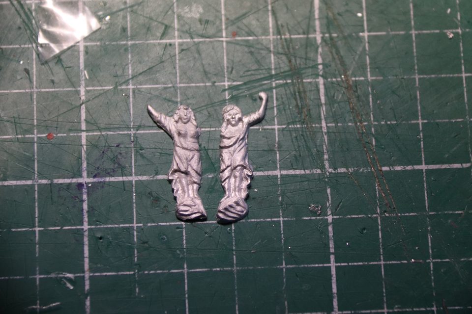 The two white metal ladies, the one on the right with an arm that is too short