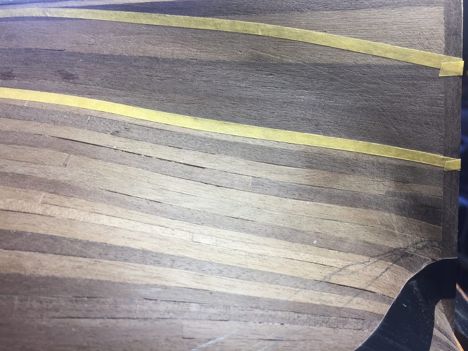 The chosen strake taped off on both sides: the two lengths of tape follow the sheer of the planking.