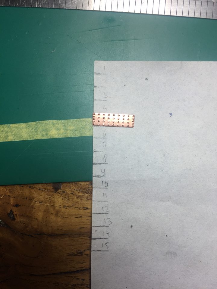 The template: a strip of paper with the width of one copper plate repeated, with the plate beside it as the measure.