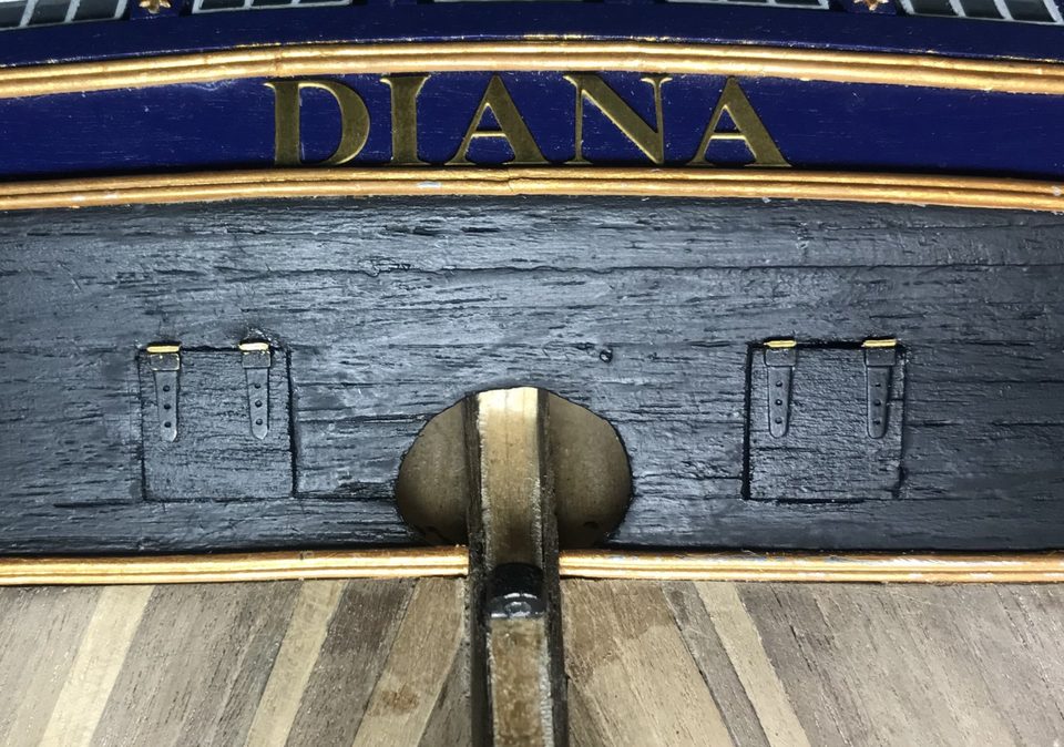 The small brass pieces above the hinges against the hull, still unpainted.