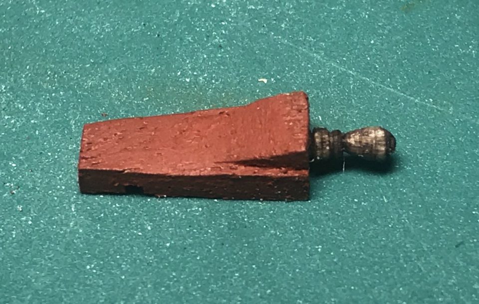 The handle on the red-painted quoin, stained walnut colour; about 4 x 1.7 mm.