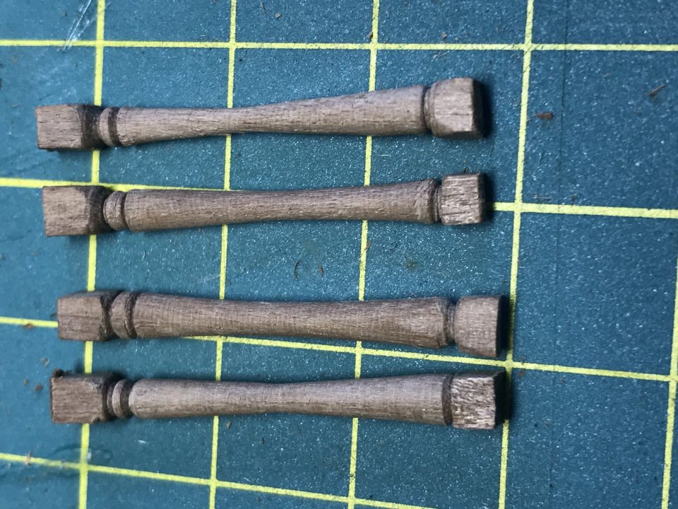 Four turned walnut rollers: a thick barrel with a narrower neck at each end.