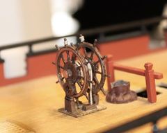 The ship's wheel on deck, with the bitts behind it