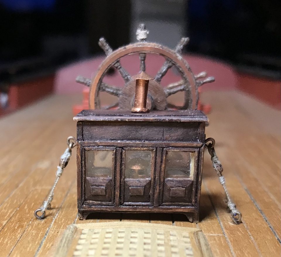 The binnacle on deck, in front of the ship's wheel