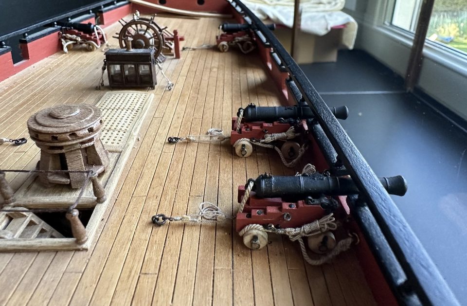 The quarterdeck with ship's wheel, binnacle and capstan, the starboard guns rigged