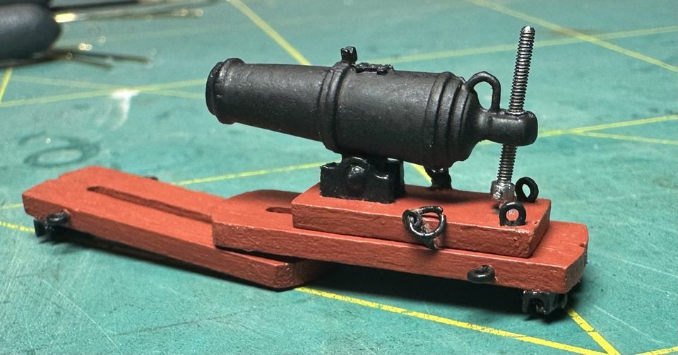 A finished carronade: blackened, with the brass trucks under the slide, the elevating screw with its pin handle and all the rings fitted.