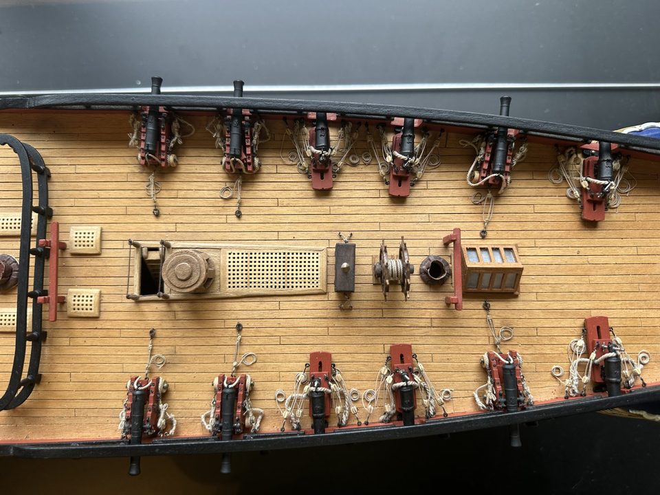 From above: 9-pounders and carronades on both sides, with capstan, grating, ship's wheel and binnacle in the middle