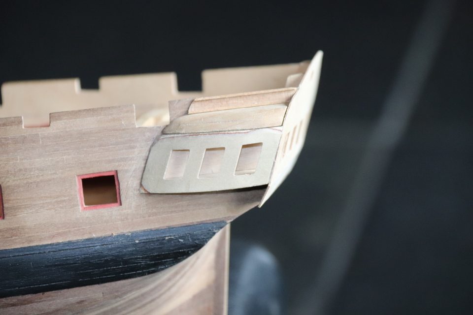 The stern after the first coat of matt black: the wale reads as a dark band below the gallery.