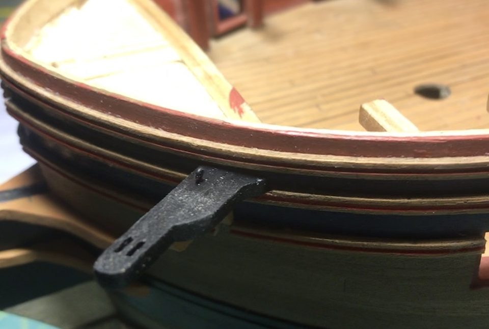 The cathead passes through the cut mouldings; the opening closes tightly around the beam.