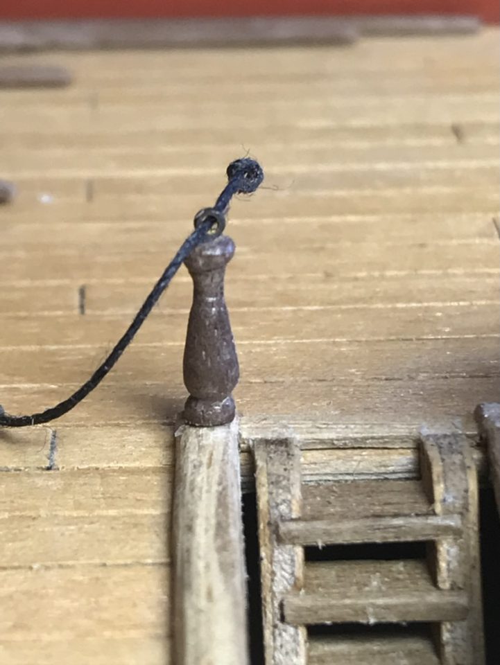Close-up of a stanchion with the brass ring at the top and the rope through it.