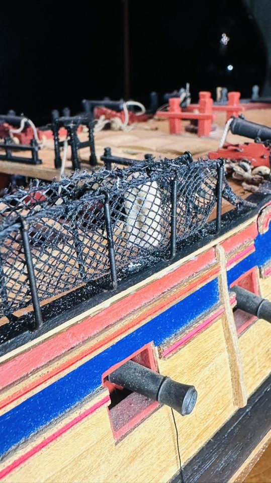 The netting on the bulwark with the first hammock in it, seen from the bow.